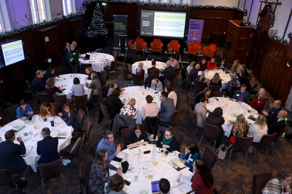 Conference participants seated at round tables.
