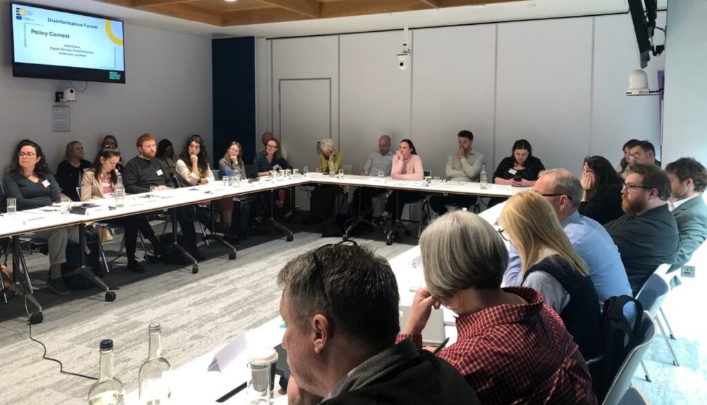 Photo of forum participants seated around a long U-shaped table